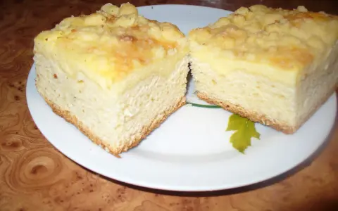 Dwa kawałki puszystego ciasta drożdżowego z kremowym nadzieniem i kruszonką, gotowe do pieca.
