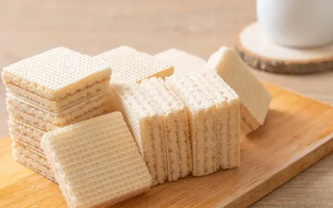 Chrupiące wafle z mlekiem w proszku i galaretką, ułożone na drewnianej desce. Idealne na deser.