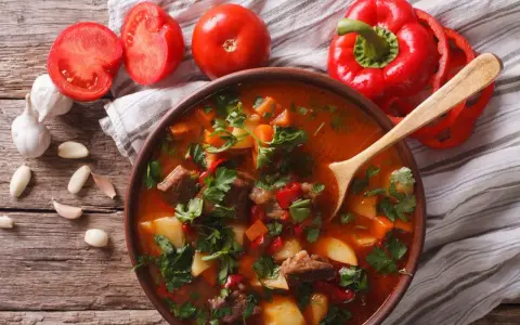Aromaticzna zupa gulaszowa przepis. Mięso, ziemniaki, papryka i pomidory w bogatym bulionie, ozdobiona natką pietruszki.