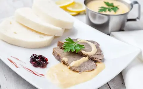 Plasterki pieczonego schabu z sosem, knedliki, konfitura z owoców leśnych i sos do schabu pieczonego w sosjerce.
