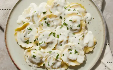 Ravioli w kremowym sosie, posypane natką pietruszki. Pyszny sos do ravioli, który zachwyca smakiem.