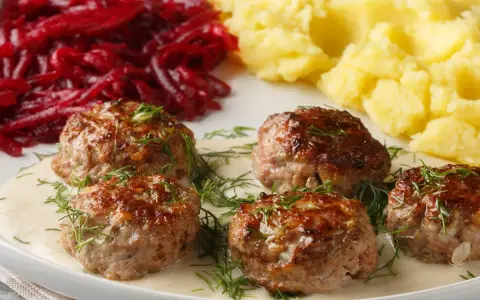Pyszne klopsy w sosie, podane z puree ziemniaczanym i buraczkami. Idealny przepis na obiad!