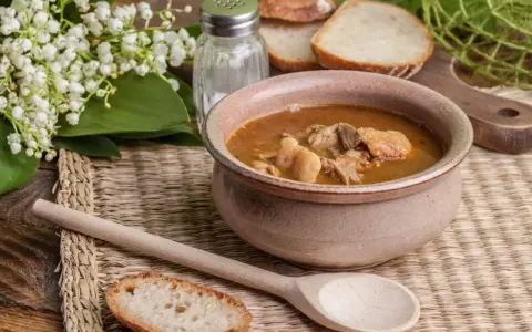 A miska gulaszowej zupy z mięsem, chlebem i konwalią. Idealne jakie przyprawy do zupy gulaszowej?