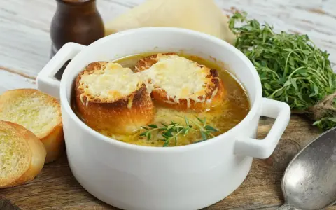 Aksamitna francuska zupa cebulowa z grzankami zapieczonymi pod serem i gałązką tymianku.