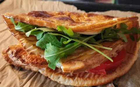 Pyszna tortilla z serka wiejskiego z rukolą i pomidorem, idealna na szybki lunch.