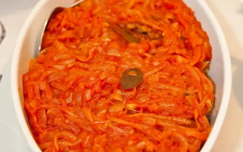 Ryba po grecku Ani Gotuje w sosie pomidorowo-cebulowym, podana w białej misie.