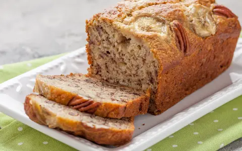 Wilgotny chlebek bananowy z olejem, udekorowany orzechami pekan i plasterkami banana. Idealny na podwieczorek.