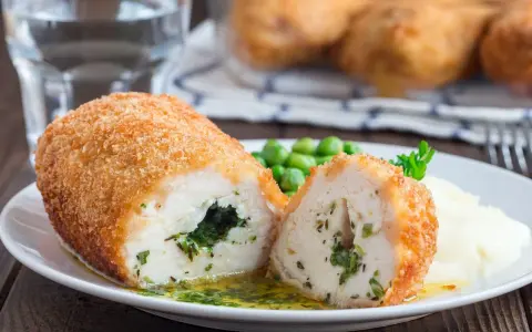 Pyszne kotlety po kijowsku, chrupiące z zewnątrz, soczyste w środku, podane z puree i groszkiem.