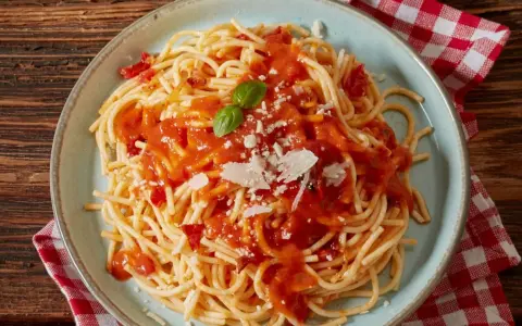 Pyszne spaghetti z sosem pomidorowym, parmezanem i listkiem bazylii. Idealne co do spaghetti na szybki obiad.