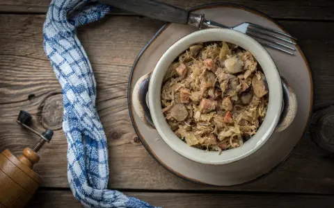Tradycyjny bigos z kapusty i mięsa, idealny do długiego gotowania. W misce widać kawałki grzybów i kiełbasy.