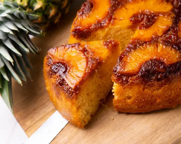 Pyszne ciasto z patelni z ananasem i karmelizowaną skórką, obok świeży ananas.
