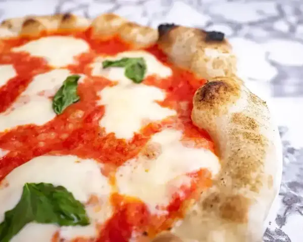 Puszyste ciasto na pizzę z sosem pomidorowym, ciągnącą się mozzarellą i listkami bazylii. Idealne na wieczór z przyjaciółmi.