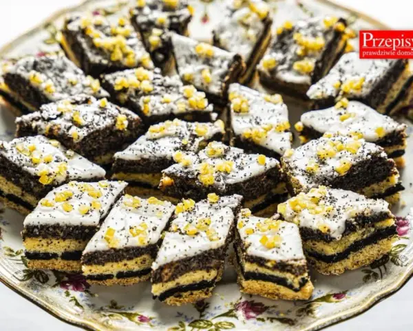 Pyszne ciastka z makiem, udekorowane lukrem i kandyzowaną skórką pomarańczową, ułożone na ozdobnej paterze.