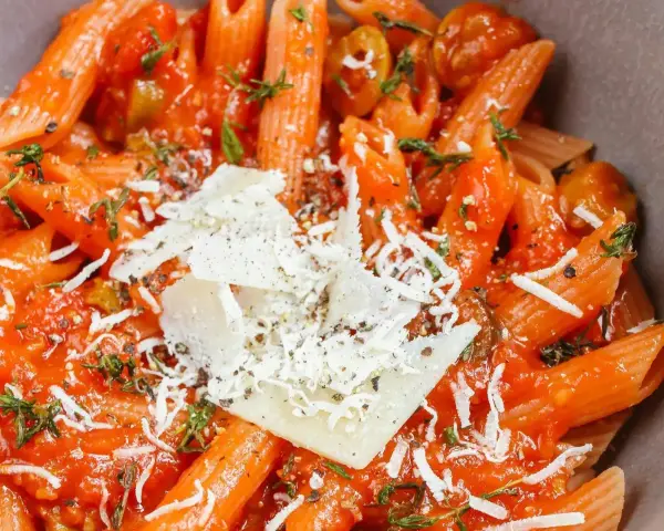 Pyszne dania z makaronem penne w sosie pomidorowym z parmezanem i ziołami. Idealne na szybki obiad.