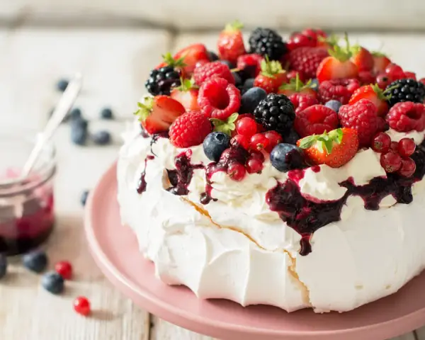 Pyszny deser Pavlova z owocami leśnymi – idealny sposób, by wykorzystać co zrobić z białek. Kremowa beza, bita śmietana i świeże owoce.