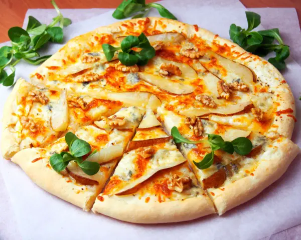 Apetyczna pizza z gruszką i gorgonzolą, ozdobiona orzechami włoskimi i świeżą rukolą. Idealna na wyjątkowy wieczór.
