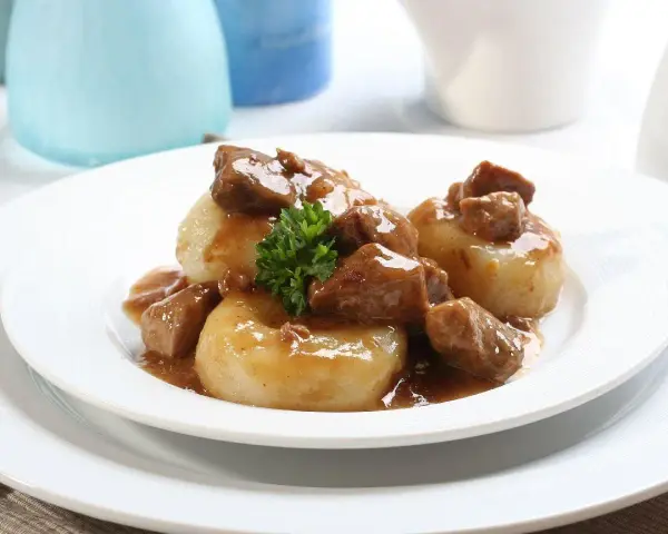 Kluski śląskie z gęstym, aromatycznym sosem mięsnym i gałązką natki pietruszki. Pyszny sos do kluski śląskie.