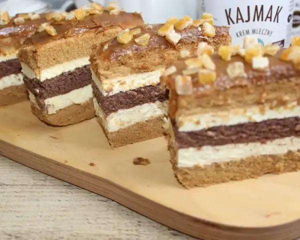 Pyszne ciasto toffi z masą kajmakową, przełożone czekoladowym biszkoptem i kremem. Udekorowane kandyzowanymi skórkami.