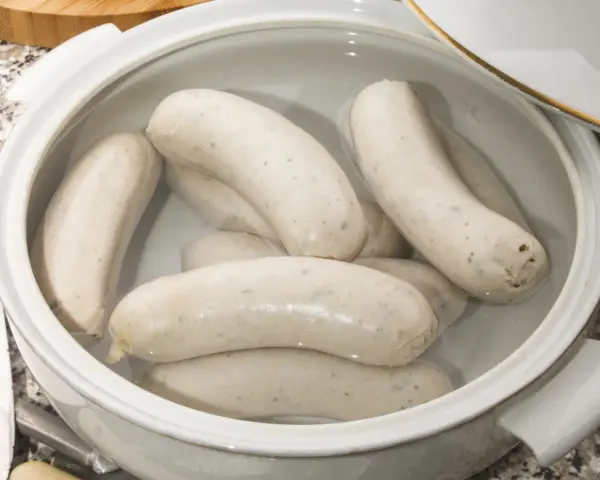 Biała kiełbasa w garnku, gotowa do przygotowania według przepisu.