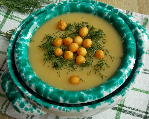 Aksamitny zupa krem z kalarepy, udekorowana chrupiącymi grzankami i świeżym koperkiem, podana w ozdobnej misce.