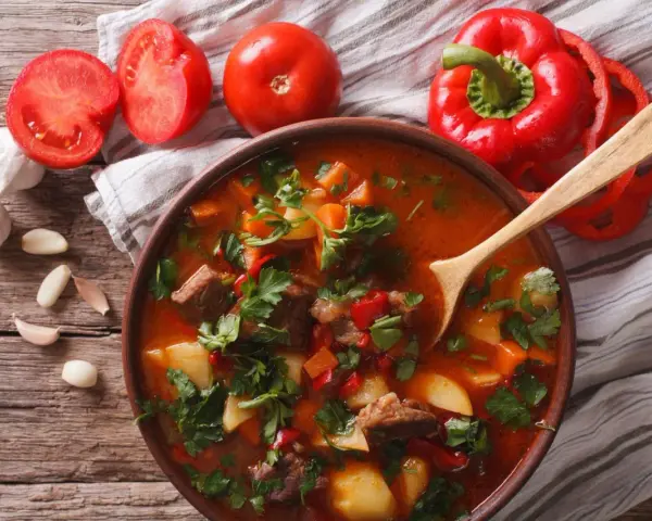Aromaticzna zupa gulaszowa przepis. Mięso, ziemniaki, papryka i pomidory w bogatym bulionie, ozdobiona natką pietruszki.
