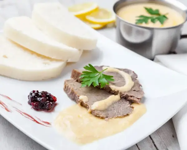 Plasterki pieczonego schabu z sosem, knedliki, konfitura z owoców leśnych i sos do schabu pieczonego w sosjerce.