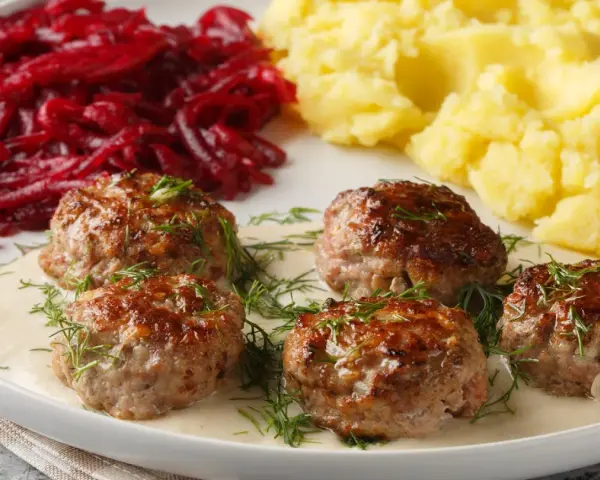 Pyszne klopsy w sosie, podane z puree ziemniaczanym i buraczkami. Idealny przepis na obiad!