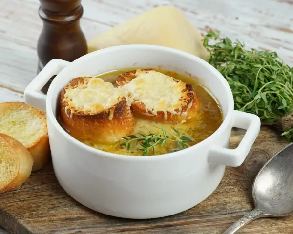 Aksamitna francuska zupa cebulowa z grzankami zapieczonymi pod serem i gałązką tymianku.
