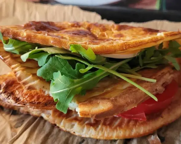Pyszna tortilla z serka wiejskiego z rukolą i pomidorem, idealna na szybki lunch.