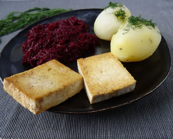 Złociste kotlety z tofu, ziemniaki z koperkiem i buraczki na talerzu.