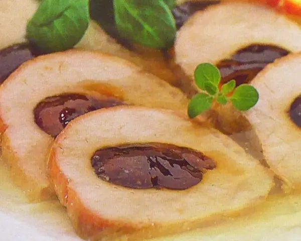 Schab ze śliwką w galarecie, elegancko pokrojony, z ziołami. Pyszne danie, które zachwyca smakiem i wyglądem.