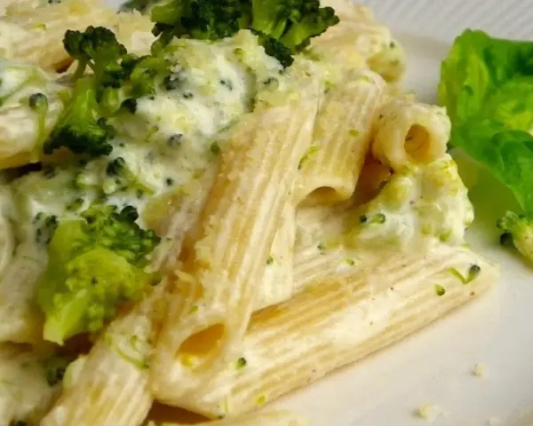 Penne z brokułami w kremowym sosie serowym, udekorowane listkiem bazylii. Pyszne danie, które zachwyci każdego smakosza.