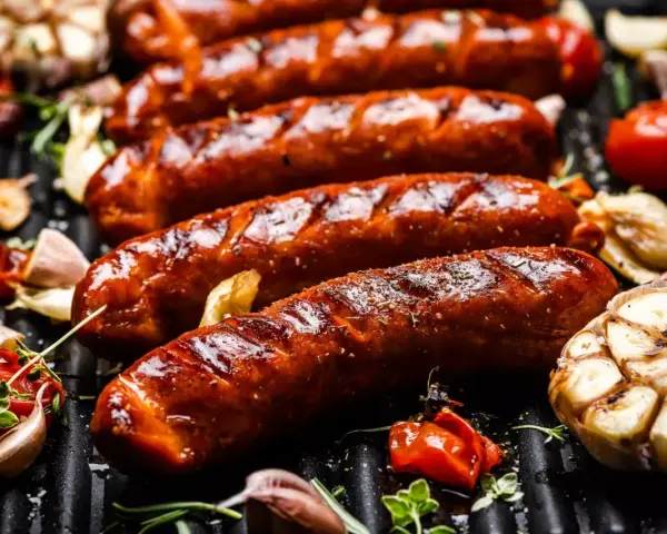 Soczyste kiełbaski na grillu, z czosnkiem i pomidorkami. Idealna odpowiedź na pytanie: jaka kiełbasa na grilla?