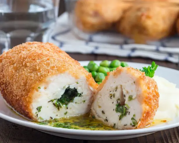 Pyszne kotlety po kijowsku, chrupiące z zewnątrz, soczyste w środku, podane z puree i groszkiem.