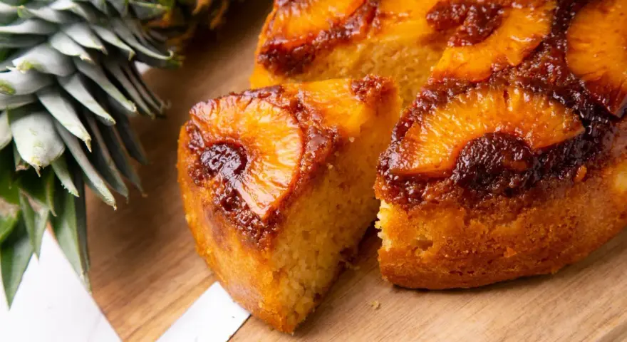 Pyszne ciasto z patelni z ananasem i karmelizowaną skórką, obok świeży ananas.