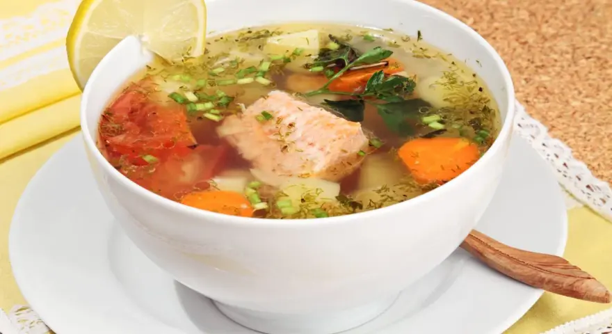 Aromatyczna zupa rybna przepis babci z łososiem, pomidorami, marchewką i ziemniakami, ozdobiona cytryną i natką.