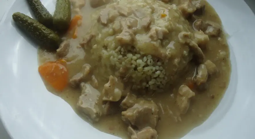 Gulasz z kaszą, podany z ogórkami kiszonymi i marchewką. Aromatyczne mięso w sosie, idealnie komponuje się z puszystą kaszą.