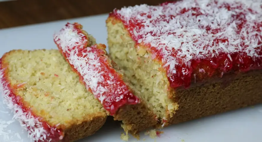Pyszne ciasto z dżemem truskawkowym i wiórkami kokosowymi, pokrojone na kawałki.