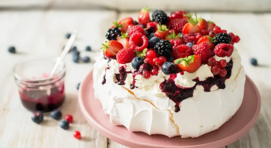 Pyszny deser Pavlova z owocami leśnymi – idealny sposób, by wykorzystać co zrobić z białek. Kremowa beza, bita śmietana i świeże owoce.