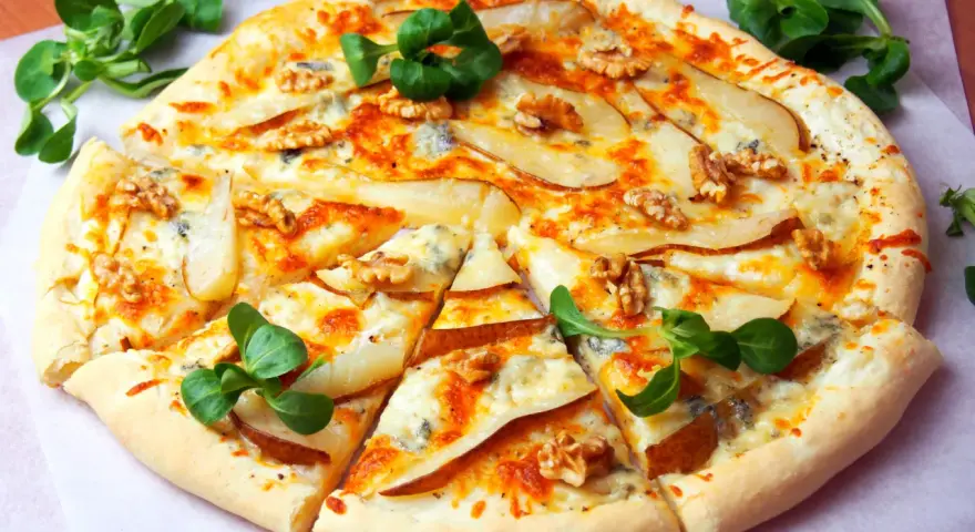 Apetyczna pizza z gruszką i gorgonzolą, ozdobiona orzechami włoskimi i świeżą rukolą. Idealna na wyjątkowy wieczór.