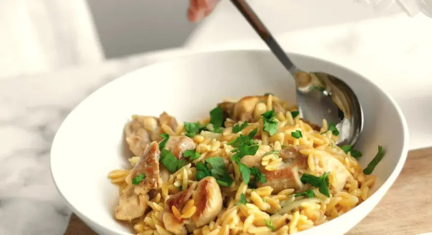 Miseczka pełna makaronu orzo z kawałkami kurczaka i posiekaną natką pietruszki. Idealny szybki sos do makaronu na obiad.
