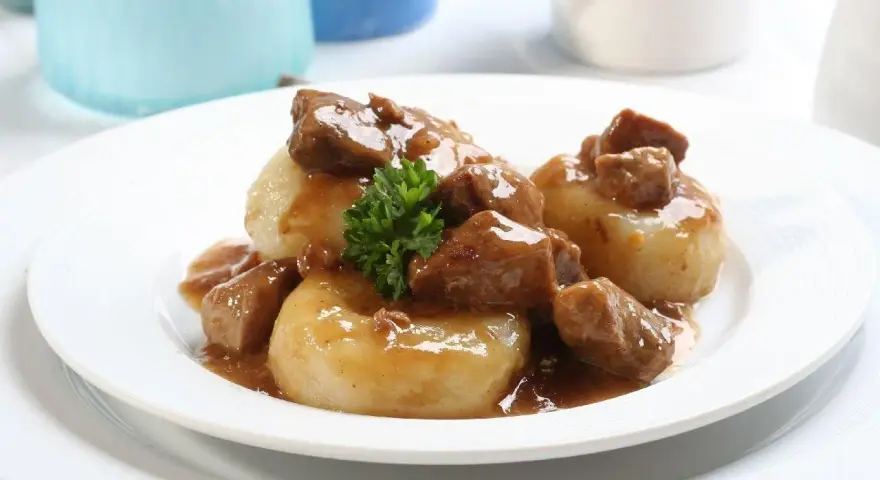 Kluski śląskie z gęstym, aromatycznym sosem mięsnym i gałązką natki pietruszki. Pyszny sos do kluski śląskie.