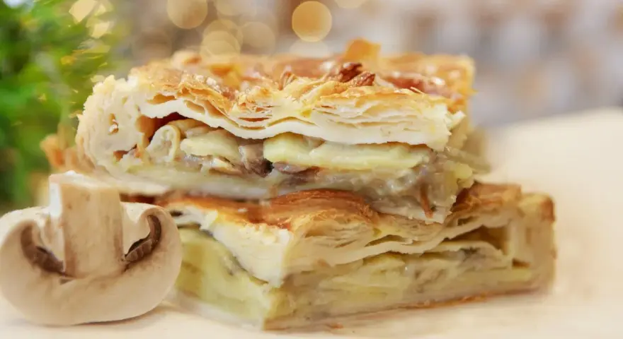 Chrupiące ciasto francuskie z kurczakiem i grzybami, podane z połówką pieczarki.