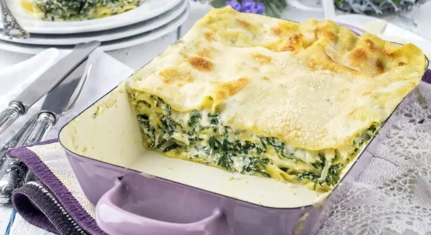 Pyszne lasagne ze szpinakiem i beszamelem, zapieczone na złoto, w fioletowym naczyniu. Idealna na rodzinny obiad.