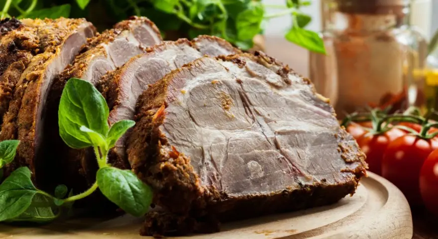 Soczysta karkówka w plastrach, pieczona z ziołami, podana z pomidorkami i świeżą bazylią.