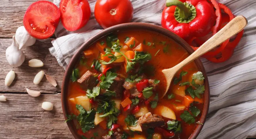 Aromaticzna zupa gulaszowa przepis. Mięso, ziemniaki, papryka i pomidory w bogatym bulionie, ozdobiona natką pietruszki.