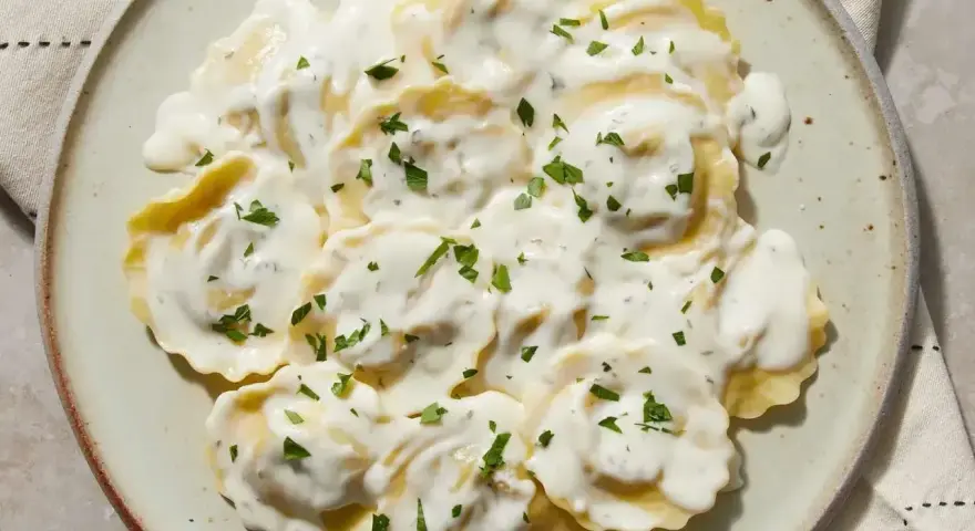 Ravioli w kremowym sosie, posypane natką pietruszki. Pyszny sos do ravioli, który zachwyca smakiem.