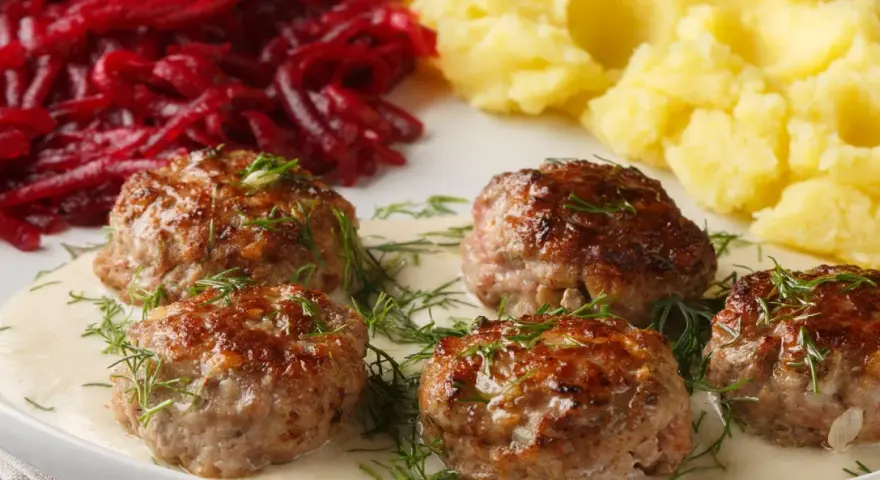 Pyszne klopsy w sosie, podane z puree ziemniaczanym i buraczkami. Idealny przepis na obiad!