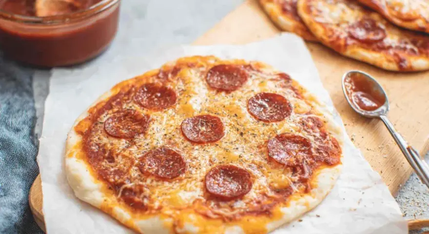 Pyszna pizza z tortilli na patelni, z serem i pepperoni, gotowa do podania. Obok sos i łyżeczka.