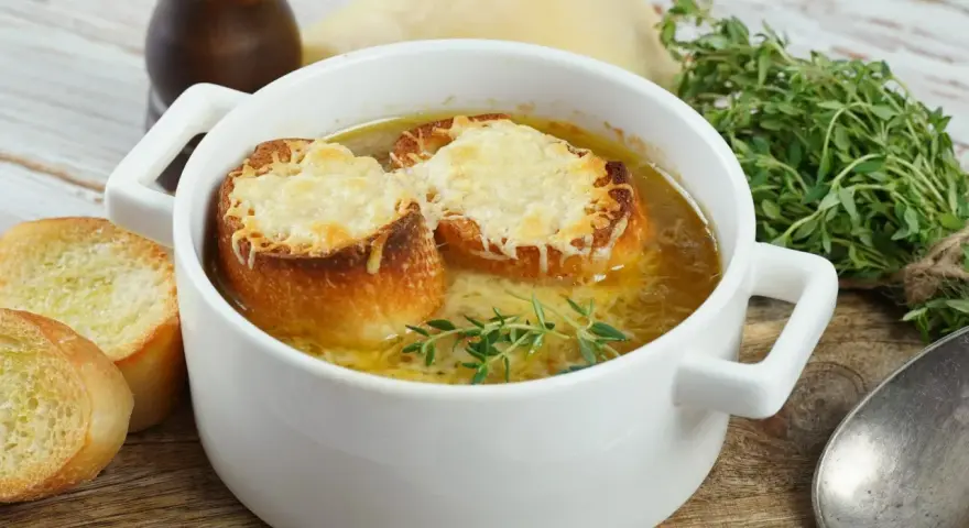 Aksamitna francuska zupa cebulowa z grzankami zapieczonymi pod serem i gałązką tymianku.